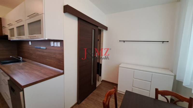 A kitchen in a 2-room apartment with sliding doors and a wooden countertop.