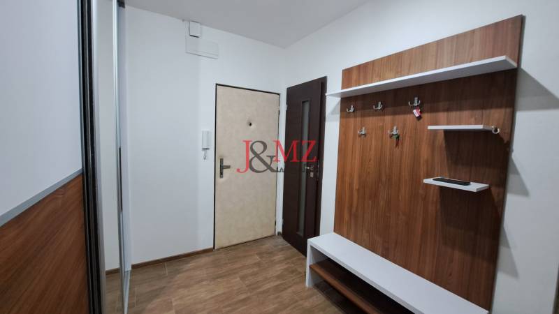 Entrance hall in a 2-room apartment with a coat rack, mirror, and security door.