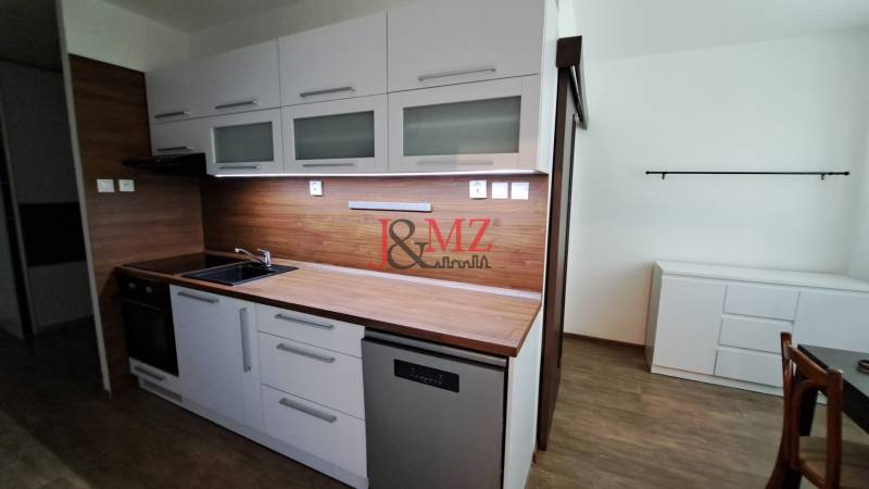 A kitchen in a 2-room apartment with a countertop and white furniture.