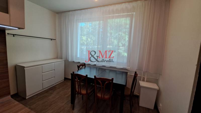 A dining table with wooden chairs and a sideboard in a 2-room apartment.