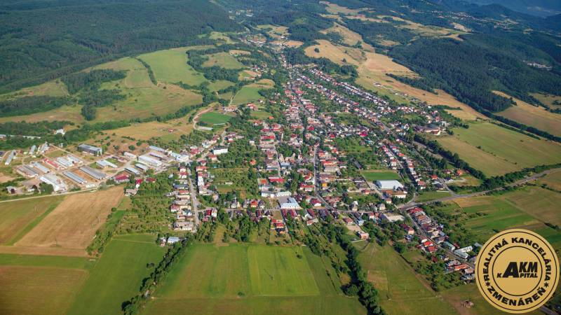 Aerial view of agricultural and forest land around Badín, surrounded by houses and buildings.