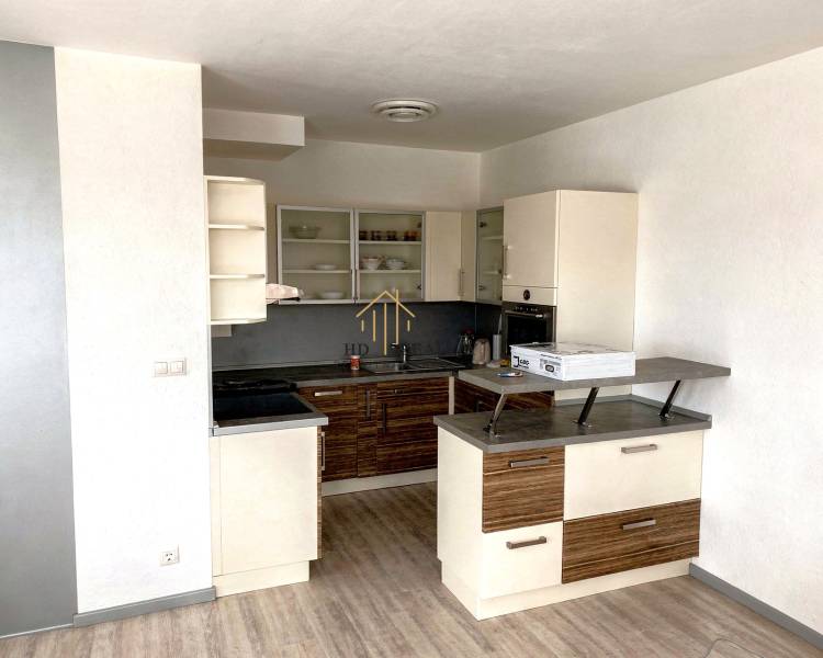 A kitchen in a 2-room apartment with a wood-patterned floor and built-in appliances.