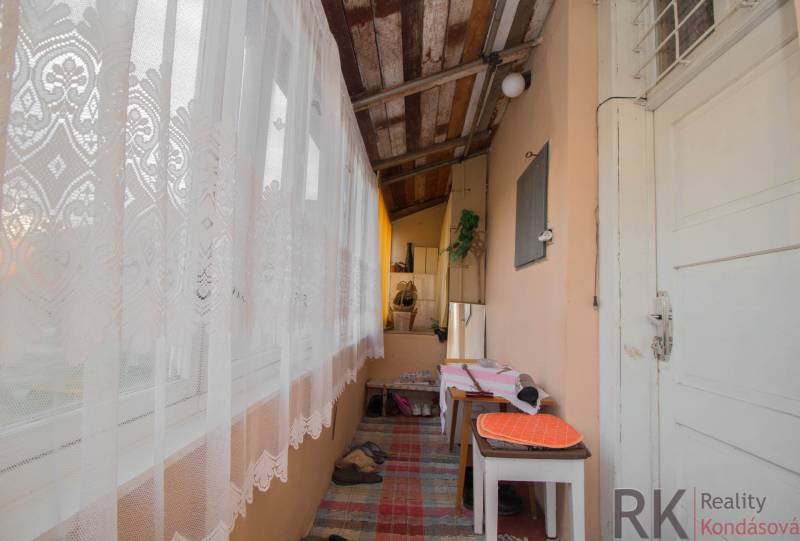 A balcony of a family house with a wooden ceiling, tables, and decorative curtains.