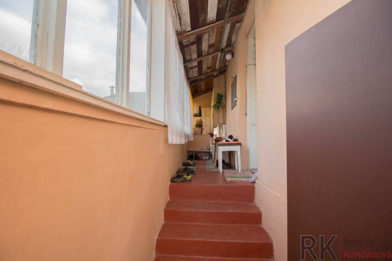 A hallway in a family house with a carpet, stairs, and a table, light walls.