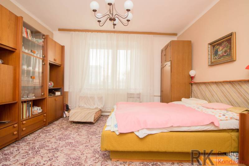 A bedroom in a family house with a carpet, furniture, a chandelier, and a painting.
