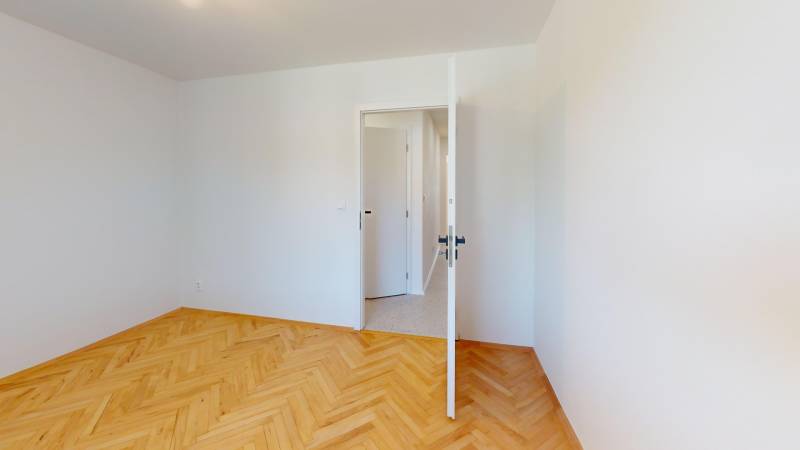 A room in a 4-room apartment with a wood-patterned floor and open doors.