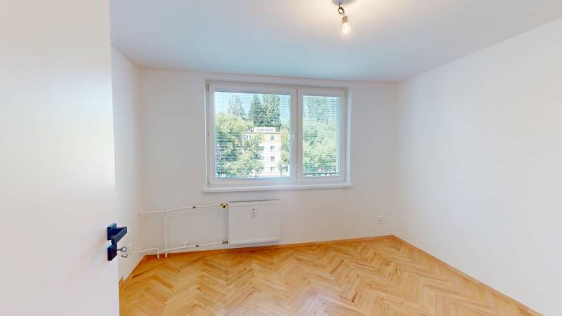 A bright room with wood-patterned flooring in a 4-room apartment, large windows with a view.