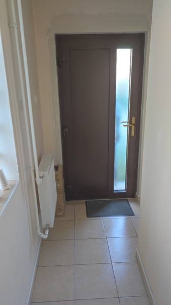 A narrow interior space with dark doors, tiles, and a radiator in an office.
