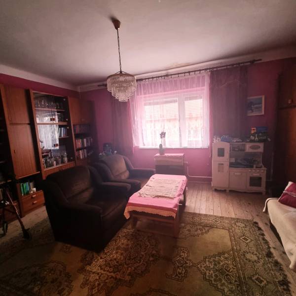 Living room of a family house with pink walls, a chandelier, a sofa, and wooden floor decor.