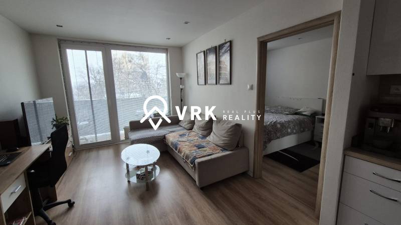 Living room with a sofa, glass table, and wooden floor decor in a two-room apartment.
