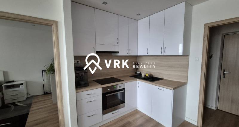 A kitchen in a 2-room apartment with a wood-patterned floor and white cabinets.