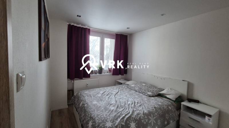 Bedroom in a 2-room apartment with a bed, nightstands, and curtains in dark colors.