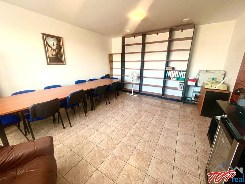 Offices with a long table, blue chairs and shelves, tiles.