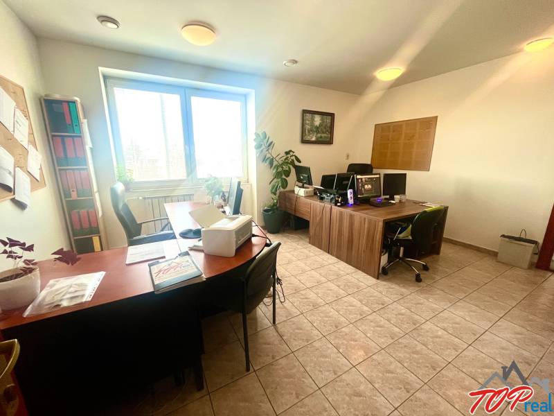 Offices with desks, computers, and plants. Tiled floor.