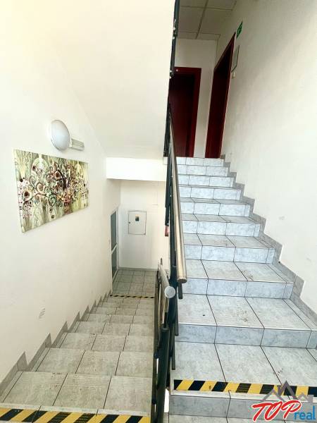 A staircase in offices with a stainless steel railing and a painting on the wall.