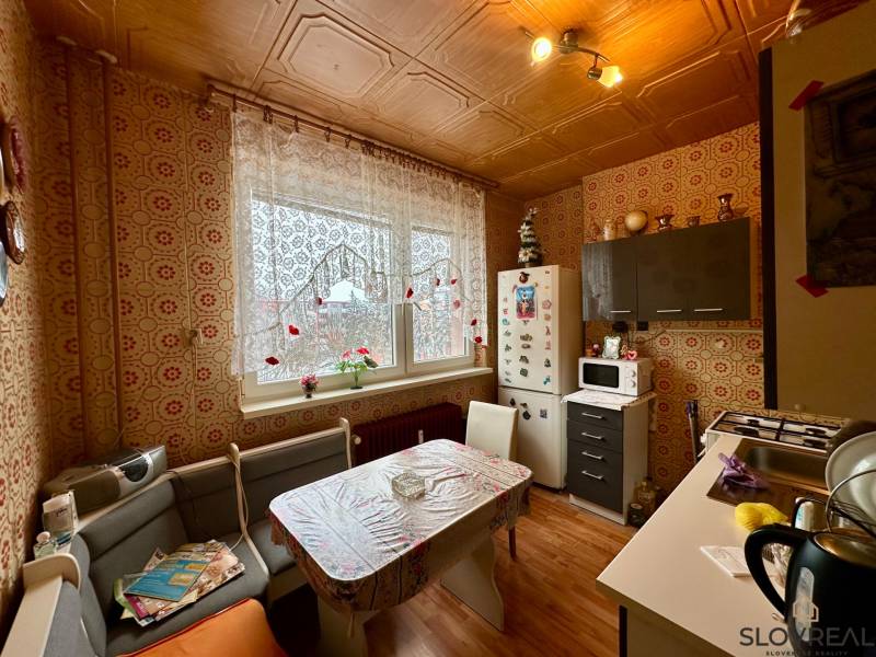 A kitchen in a 3-room apartment with vintage wallpaper and a wooden decor floor.