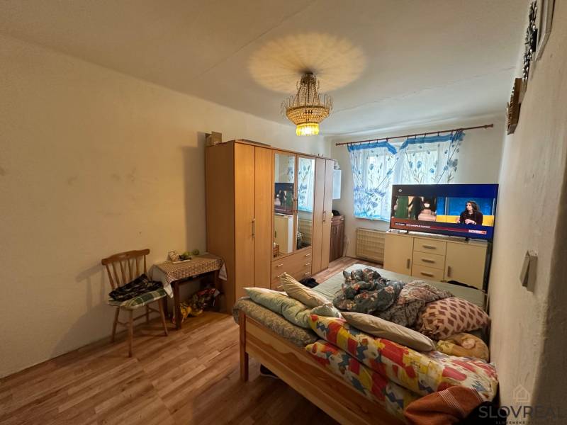 Bedroom with a bed, wardrobe, and television in a 3-room apartment, floor with wooden decor.