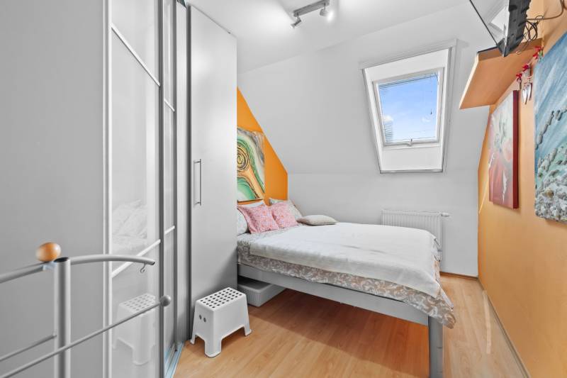 A small bedroom in a family house with a bed, a wardrobe, and colorful walls.