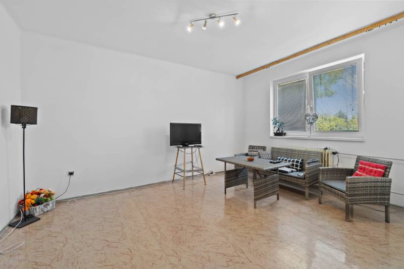 Living room in a family house with rattan seating and a television on a stand.