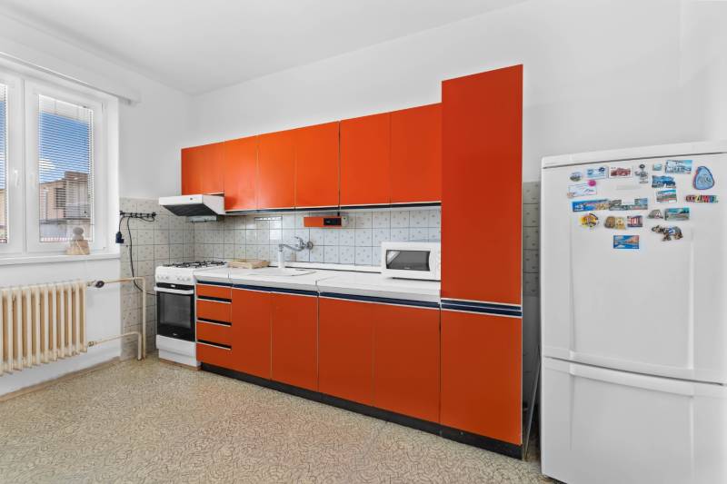 A kitchen in a family house with a stove, microwave, and orange cabinets.