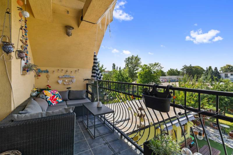 A family house balcony with comfortable seating, overlooking the garden and greenery.