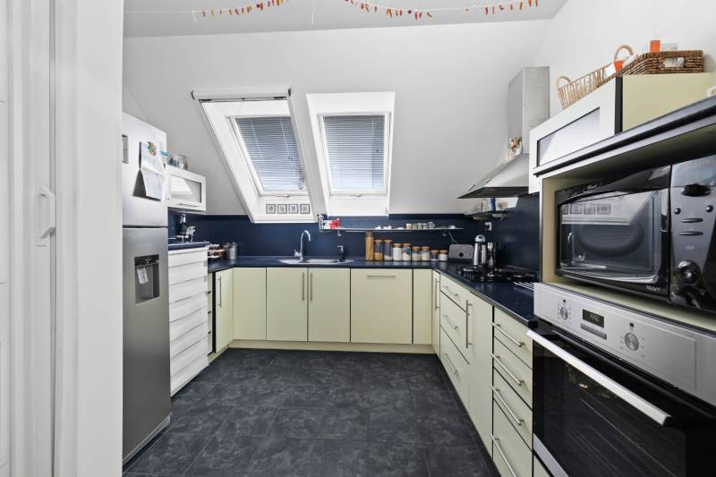 A kitchen in a family house with equipment, slanted roof windows, and appliances.