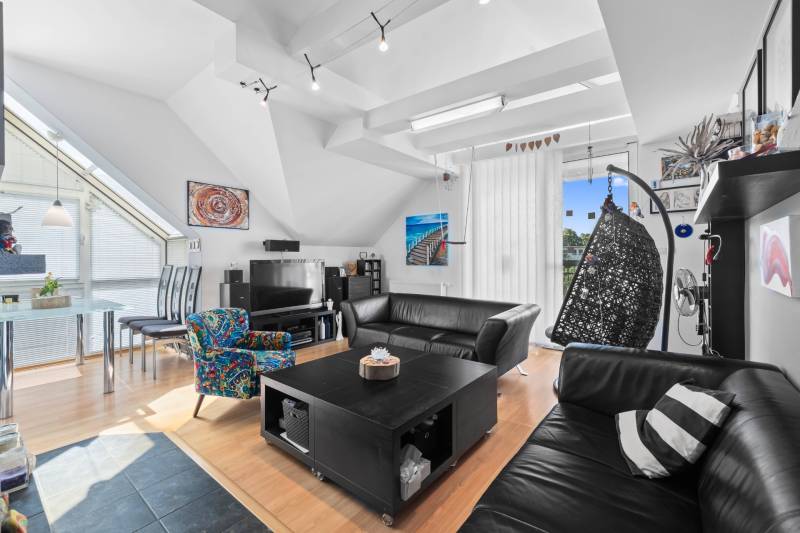 A living room in a family house with leather sofas, a rocking chair, and a dining table.
