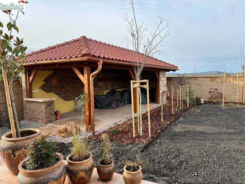 A family house in Bratislava - Jarovce with a garden gazebo and clay pots in the yard.