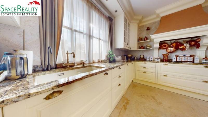 A kitchen in a family house with decorative elements, light cabinets, and a granite countertop.