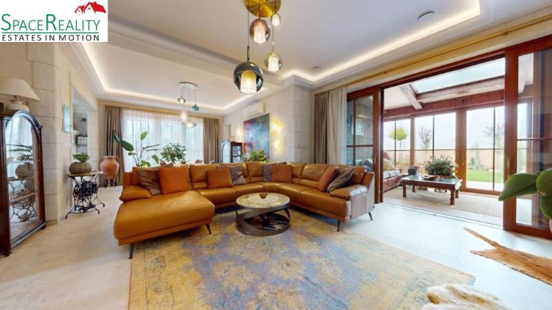 Living room in a family house with a large window, leather sofa, and plants.