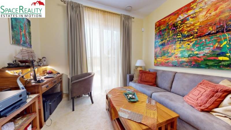 Living room of a family house with a sofa, a colorful painting, and a desk.