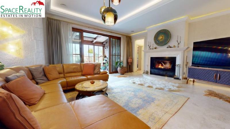 Living room in a family house with a fireplace, large sofa, and television.