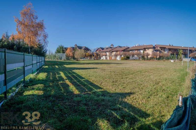 A residential plot in Veľká Lomnica with a lawn, fence, and views of the surrounding houses.