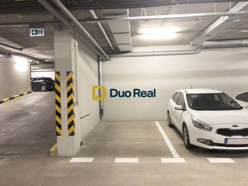 Parking spot in the garage with a white car and labeled Duo Real.