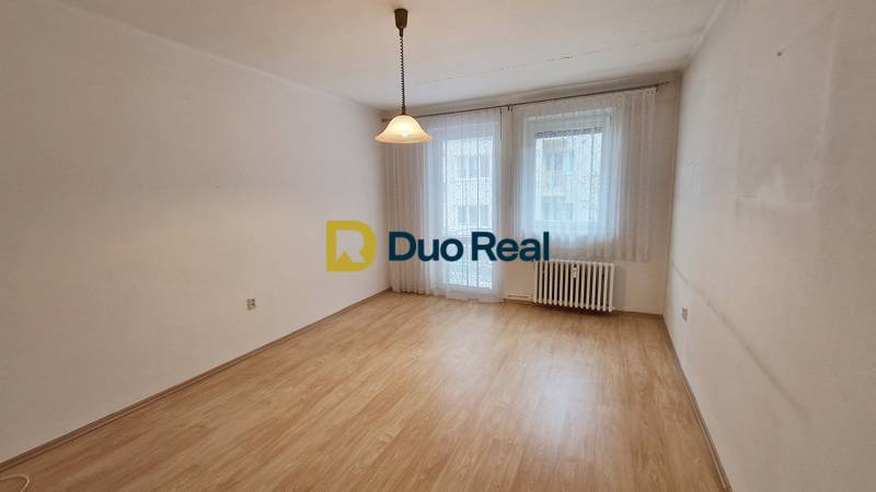 A room with windows and curtains, a floor with wooden decor, a light fixture, a radiator.