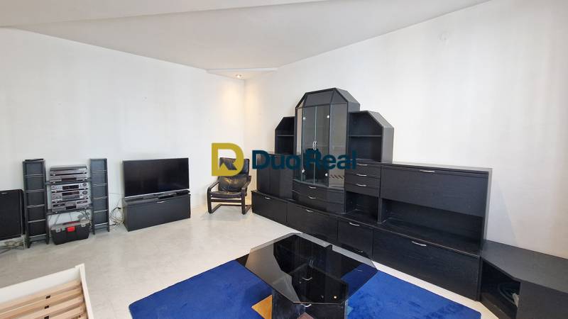 Living room in a 3-room apartment with black furniture and TV, blue carpet.