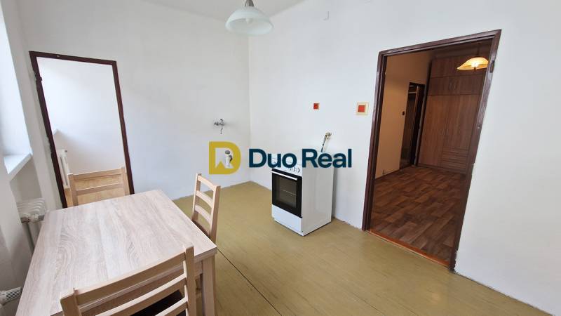 A kitchen with a gas stove, table, and chairs in a 3-room apartment.