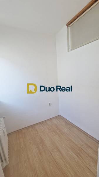 A small room in a 3-room apartment with a wood-patterned floor and a radiator.