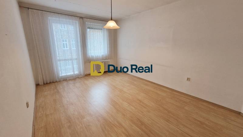 A spacious room with a wooden decor floor and curtains in a 3-room apartment.