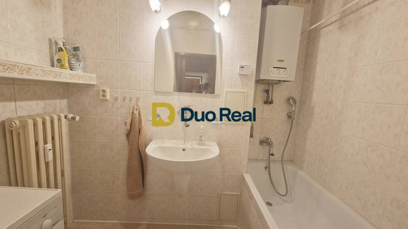 Bathroom with a shower, sink, radiator, and gas boiler in a 3-room apartment.