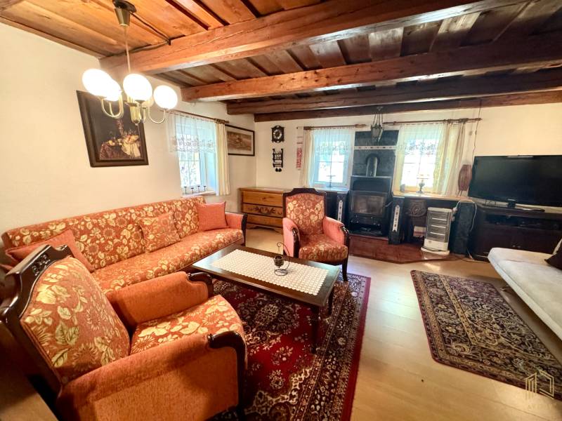 Living room in a family house with a wooden decor floor, cozy furnishings, and a wooden ceiling.