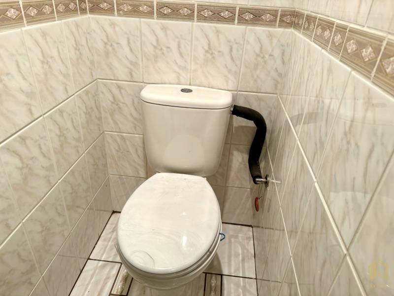 Ceramic tiles with a pattern and a toilet in a family house.