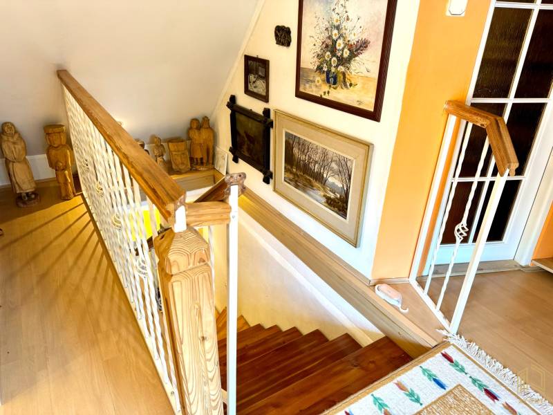 Interior staircase with decorative statues and paintings, floor with wooden decor.