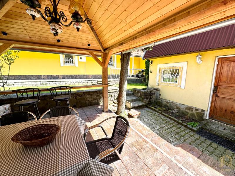 The garden of a family house in Vrbovce with a covered seating area and a yellow facade.