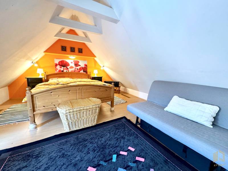Attic bedroom in a family house with a wooden decor floor and an orange wall.