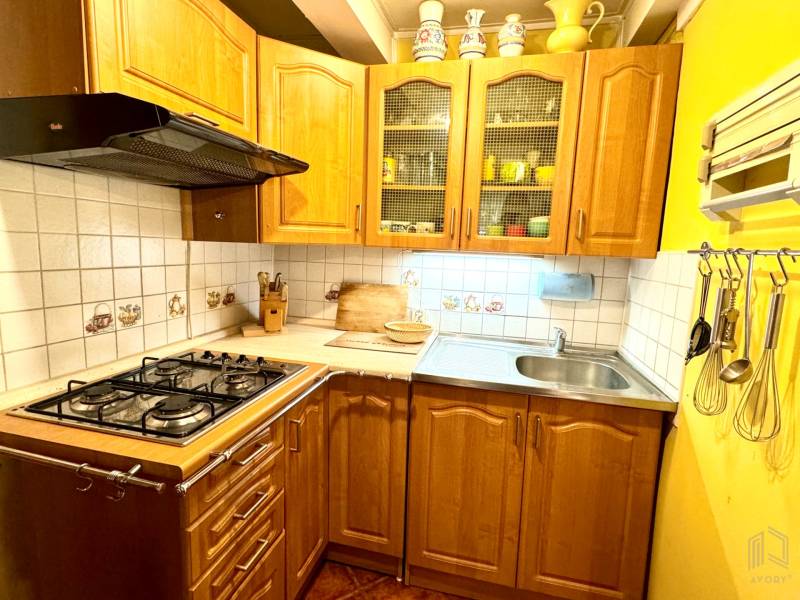 A kitchen in a family house with light wood decor and ceramic tiles.