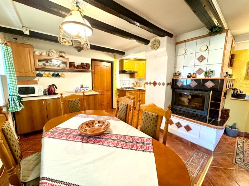 A kitchen in a family house with a stove, fireplace, wooden furniture, and decorative placemats.