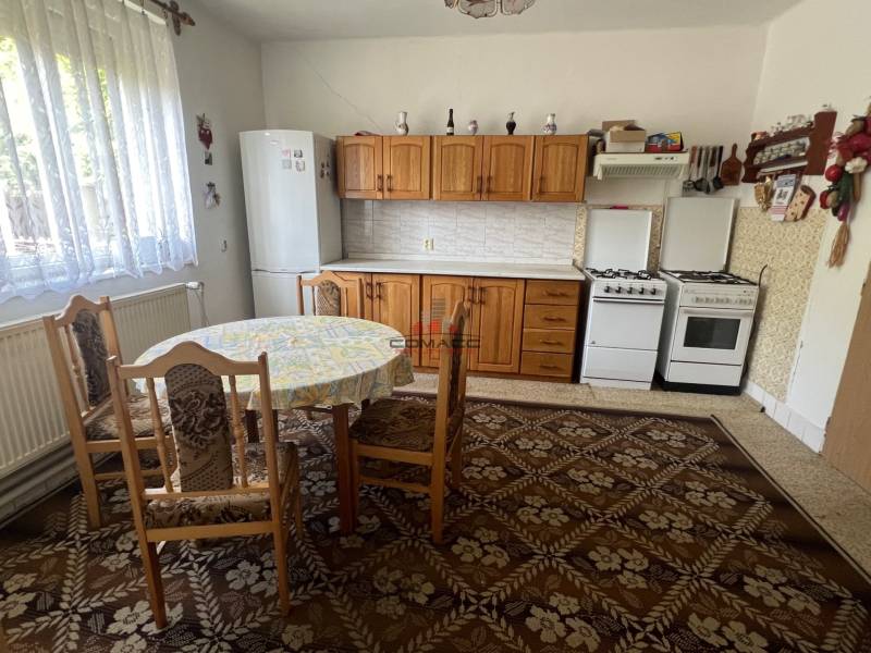 Kitchen in a family house with a dining table, wooden cabinets, and a gas stove.