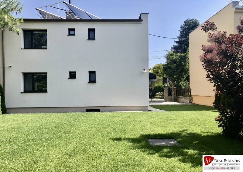 A view of a house with a lawn in Most pri Bratislave, solar panels on the roof.