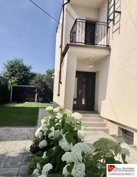 A garden with white flowers and an entrance to a house in Most pri Bratislave.